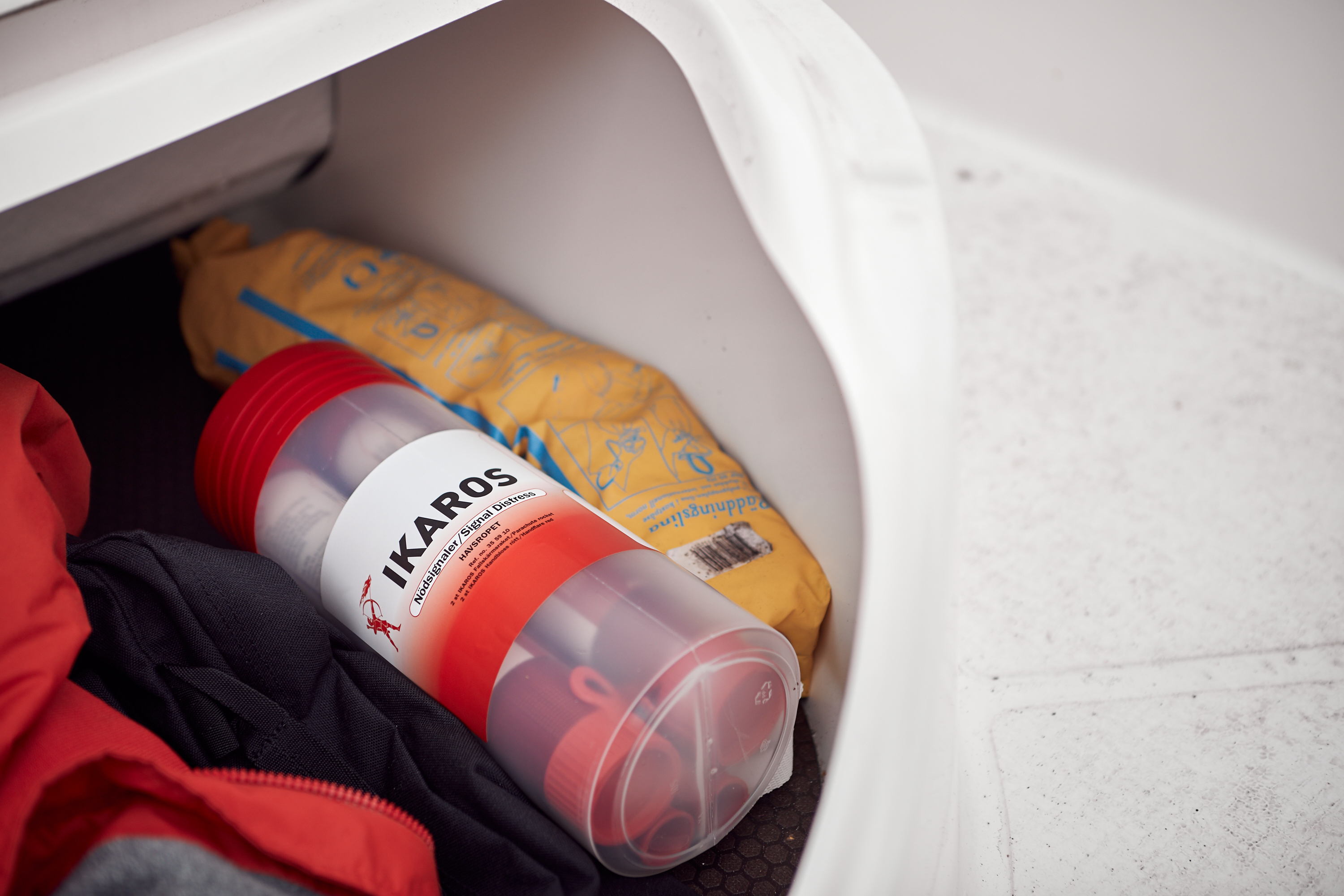 A close-up picture of an emergency kit containing distress flares placed in a small, white box together with a life jacket.