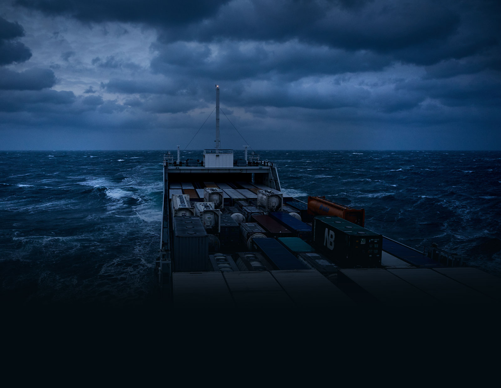 A close-up picture of a lonely cargo vessel out on a dark, dramatic sea in the middle of the night. No marine flares or distress signals are visible.